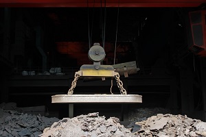 magnetic lifter on a cord above a bunch of dark material