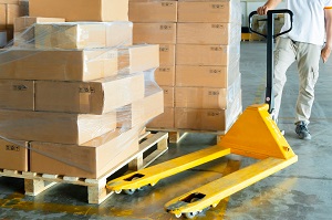 pallet truck next to a loaded pallet and a worker in the background