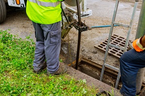 hose from a flushing vehicle hanging in an open sewage
