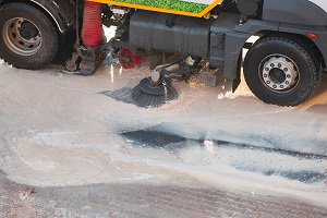 rotating brush at a street cleaning vehicle absorbing light sandy sludge from the street