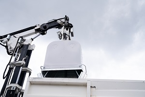 crane with glass container above an opened multi-chamber waste collection vehicle