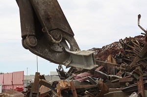 mobile scrap shear while cutting a steel girder above a scrap metal stack