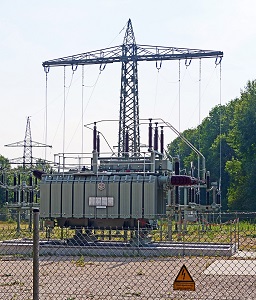 transformer behind a fence with a pylon in the background