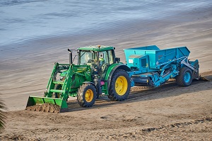 tractor with loading shovel and trailer in beach cleaning operation