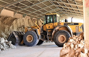 wheel loader in an open hall in front of bunches of sand